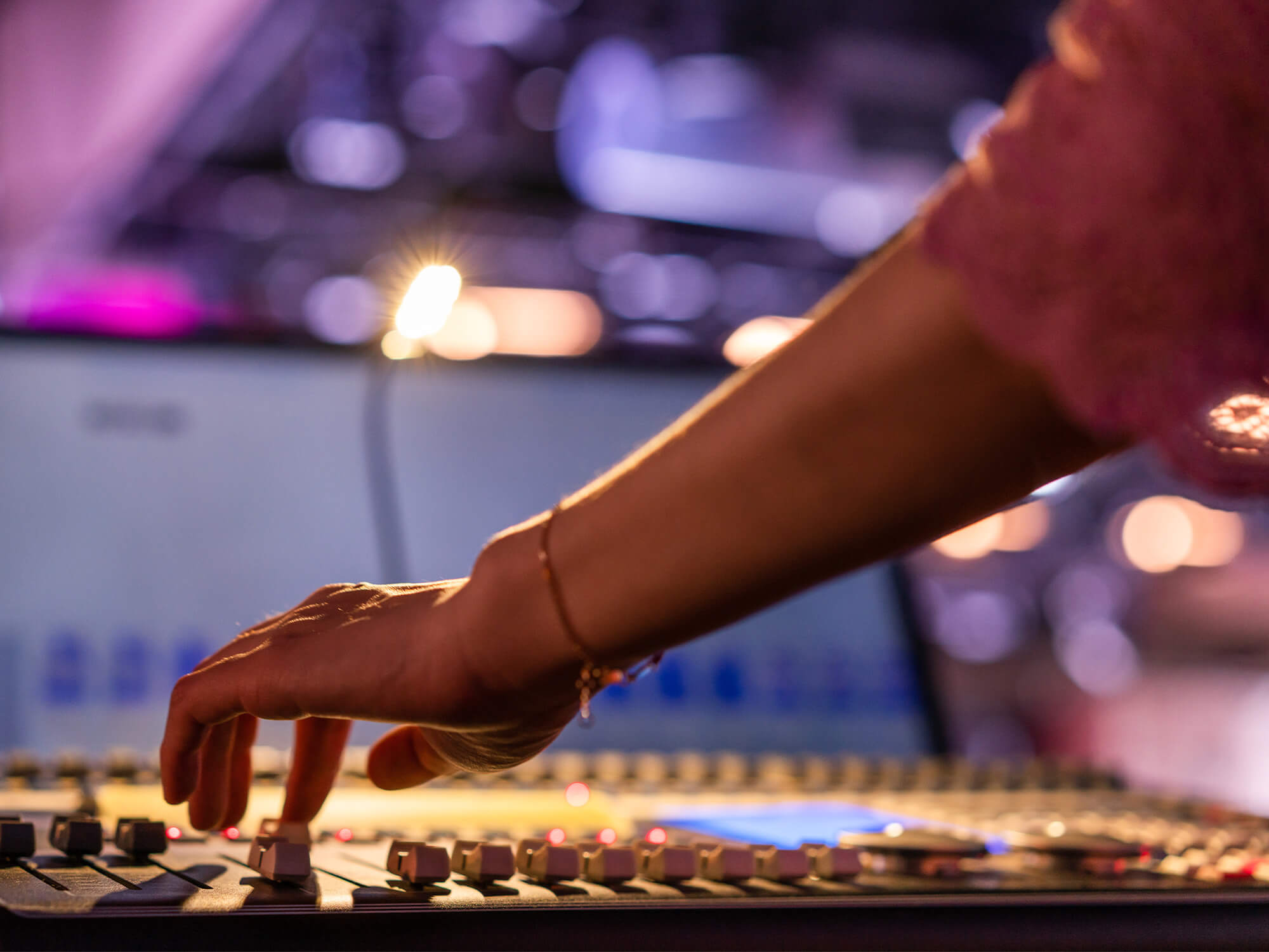 A hand on a recording console adjusting a slider